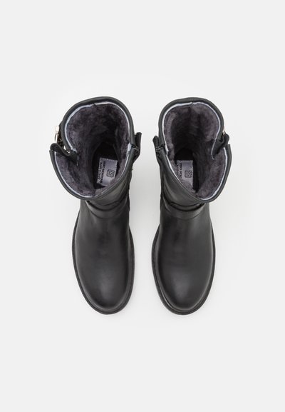 Botas de tobillo de cuero negro con un suave forro gris, punteras redondeadas y cremalleras laterales. Textura lisa sin patrones visibles ni acentos de hardware.