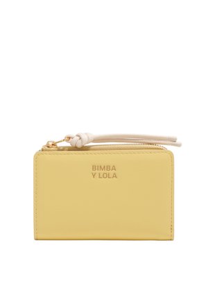 Cartera amarilla de cuero con cremallera, tira de agarre blanca anudada y texto "BIMBA Y LOLA" en relieve en el frente.