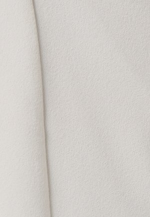 Tejido texturizado en color blanco roto con un acabado suave y mate. La superficie tiene una ligera textura que realza su cualidad táctil.