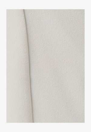 Tejido texturizado en color blanco roto con un acabado suave y mate. La superficie tiene una ligera textura que realza su cualidad táctil.