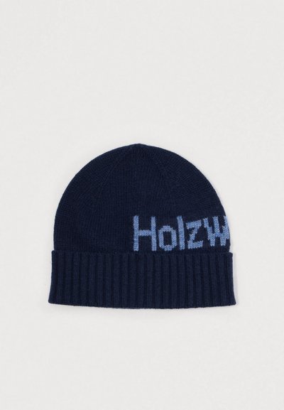 Bonnet en tricot bleu marine avec texture côtelée et détail imprimé « Holzw » en bleu clair. Forme classique, matériau doux adapté aux temps froids.