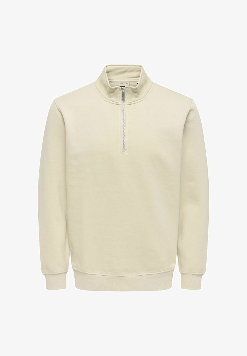 Gaiši bēšs pulovers ar augstu apkakli, priekšpusē pusciets rāvējslēdzējs, garām piedurknēm, ribota adījuma aprocēm un apakšu, izgatavots no gludas auduma.