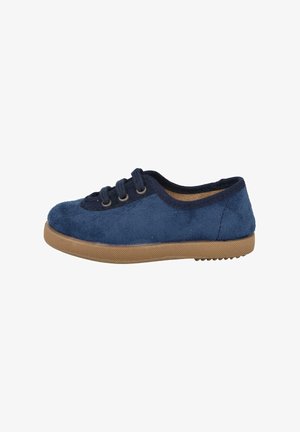 Zapato de gamuza azul marino con punta redonda, dos ojales y suela de goma marrón texturizada. Diseño minimalista con superficie suave.
