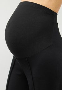 Leggings negre dintr-un material elastic, cu un talie înaltă, un design conturat și cusături vizibile pentru o potrivire personalizată.