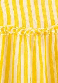 Tela de rayas verticales amarillas y blancas con un detalle de costura con volantes en el medio.