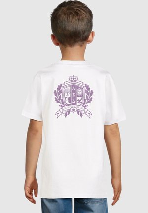 T-shirt bianco con una grafica viola sul retro, che include uno stemma con alberi, un sole e il testo "SEGUITA I TUOI SOGNI."