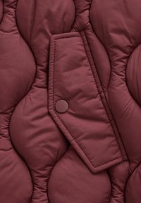 Gekwaakt bordeauxrode jas met een knoopsluiting flapzak, voorzien van afgeronde vulling en een glad oppervlak. Geaccentueerd met subtiele stiklijnen.