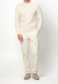 Maglione girocollo lavorato a maglia color beige chiaro abbinato a pantaloni larghi color beige chiaro e scarpe da ginnastica beige. Design semplice, texture morbida.