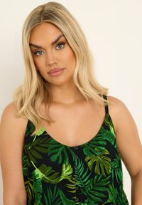 Ärmfri svart klänning med grönt tropiskt bladmönster, med rundad halsringning och knappdetalj fram. Slät textur och andningsbart tyg.