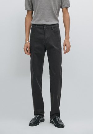 Dark grey straight-leg trousers made of cotton, featuring a classic five-pocket design and button closure. Worn with a grey knit top.