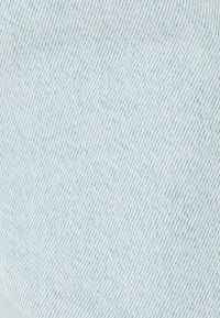 Tela de denim azul claro con una sutil textura, que muestra patrones de costura en diagonal y ligeras variaciones en el tono.