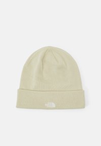 Lys beige strikket hue med en foldet kant. Har et lille hvidt logo-mærke foran, glat tekstur og enkelt design.