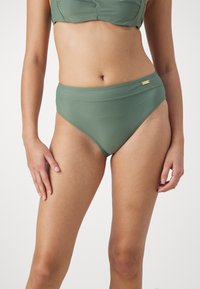 Høyt liv bikini-bunn i olivengrønn, laget av glatt stoff. Har en brettet midjebånd og subtilt detalj i gulltone.