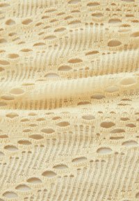 Tessuto in pizzo giallo chiaro con un motivo aperto e fori ovali, texture fine e dettagli intricati nella tessitura.