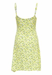 Robe d'été jaune à fines bretelles, avec un motif de citrons et de feuilles vertes sur fond blanc. Coupe trapèze avec un ourlet évasé.