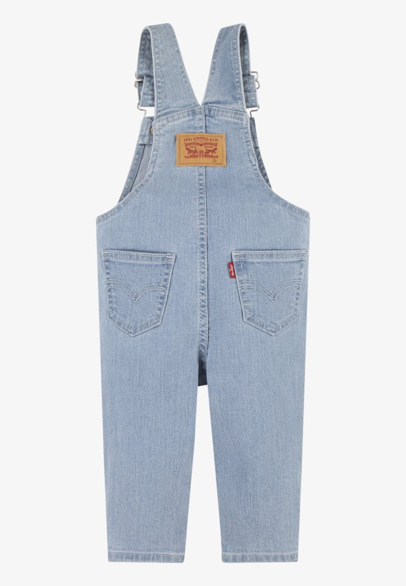 Pantalones de tirantes de mezclilla de color azul claro con tirantes ajustables, bolsillo frontal y dos bolsillos traseros. Presenta una etiqueta de cuero con marca en la parte posterior.