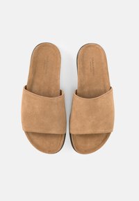 Ζευγάρι ταμπά δερμάτινα σανδάλια χωρίς κορδόνια, με φαρδιές λουρίδες, επίπεδες σόλες και την ένδειξη «Vagabond Shoemakers» τυπωμένη στις εσωτερικές σόλες.