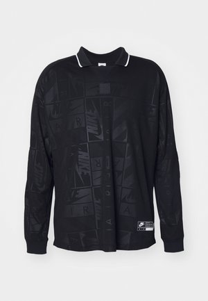 Schwarzes Poloshirt mit langen Ärmeln, das ein strukturiertes Muster, einen kontrastierenden weißen Kragen und ein Nike-Logo auf der unteren linken Seite hat.