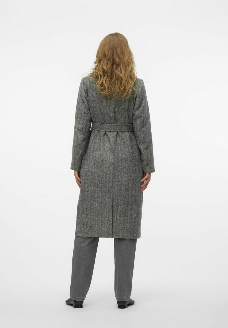 Manteau long en mélange de laine gris avec une taille ceinturée, texture à côtes verticales, manches longues et coupe droite, porté sur un pantalon gris.