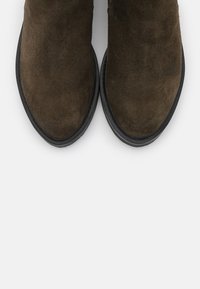 Ruske nubuk ankle čizme s okruglim prstima i teksturiranom završnom obradom, s crnom gumenom potplatom i minimalnim detaljima šivanja.