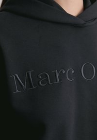 Czarna bluza z kapturem z haftowanym napisem "Marc O'". Miękka faktura i swobodny design. Posiada duży kaptur. Materiał wydaje się być mieszanką bawełny.