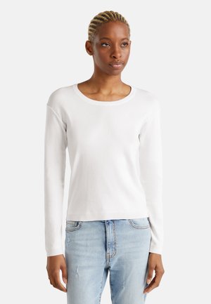 Weißer, langärmeliger Pullover aus einem weichen Strickmaterial mit einem runden Halsausschnitt und gerippten Bündchen, kombiniert mit hellblauen, ausgewaschenen Jeans.