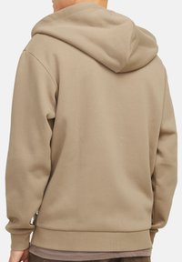 Beige bomulds hættetrøje med afslappet pasform, ribbede håndled og en tekstureret finish. Designet inkluderer en dobbeltlaget hætte.