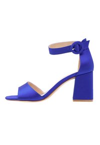 Královsky modré otevřené sandály na vysokém podpatku s ankletovou páskou a kulatou sponou, blokovým podpatkem a krémovou vnitřní podrážkou, boční pohled na bílém pozadí.
