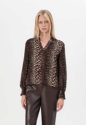 Bluse med leopardmønster i lett stoff, med v-hals, lange puffede ermer og elastiske mansjetter. Sammen med mørkebrown bukser.