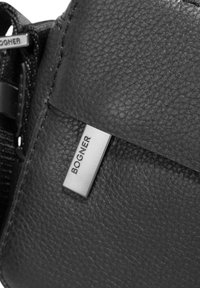 Svart läderväska med texturerad yta, med en metallisk etikett präglad med "BOGNER." Stängningen har en slät, rektangulär design.