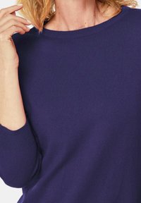 Strickpullover in Dunkelmarine mit weitem Rundhalsausschnitt und gerippten Bündchen. Das Material wirkt weich und strukturierend, mit einem lässigen Schnitt.