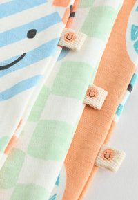 Baumwollstoffmuster in Pastellfarben: blaue Streifen, grüne Karos und orange mit Mustern. Mit Smiley-Labels an den Rändern.