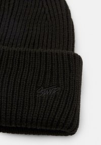 Zwarte gebreide beanie met een geribbelde textuur en een omgeslagen rand. Bevat een klein, reliëflogo in het zwart op de rand.