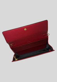 Portafoglio in pelle rossa con finitura texturizzata, dotato di una tasca con zip, numerosi slot per carte e chiusura a scatto dorata.