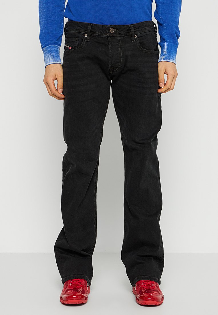 Jeans en denim noir avec une coupe droite classique, dotés d'une fermeture à bouton à l'avant, de poches arrière et de détails de couture subtils.