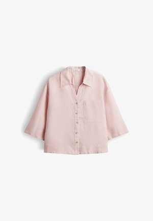 Camicia rosa chiaro a maniche corte con bottoni, una tasca sul petto e colletto appuntito, mostrata distesa su sfondo bianco.