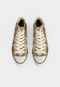 Ζευγάρι sneakers ψηλής κοπής με μπεζ και καφέ καμουφλάζ σχέδιο, λευκά κορδόνια και λαστιχένιες μυτούλες, σε θέα από πάνω.