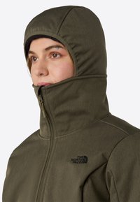 Olive green hooded jacket with a high collar, zip closure, and black logo on the chest. Fabric appears textured and durable.