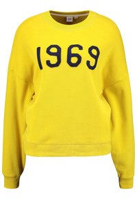 Felpa gialla con ricamo in blu navy "1969". Presenta un collo rotondo, maniche lunghe e una vestibilità rilassata. Realizzata in morbido cotone.