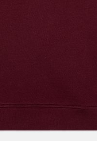 Burgundi színű pulóver anyag, sima textúrával, bordázott szegéllyel. Egyszerű dizájn, látható minták vagy díszítések nélkül. Egyszínű szövet.