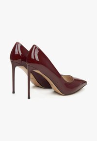 Glanzende bordeaux patent leren high heels met een spitse neus, slanke stilettohak en een subtiele uitsnede aan de voorkant.