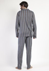 Conjunto de pijama de rayas en azul, gris y beige, con mangas largas y cintura elástica. Tejido suave con un ajuste relajado y diseño de pierna recta.