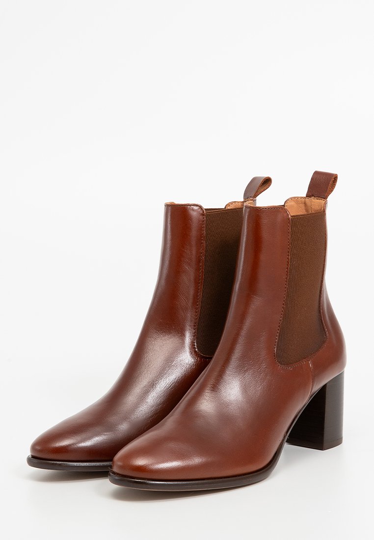 Stivaletti in pelle marrone con finitura liscia, pannelli laterali elastici e tacco spesso. Design a punta.