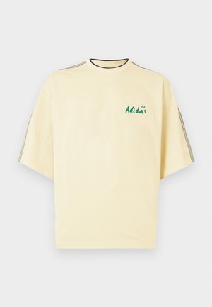 Camiseta de algodón amarillo claro con mangas cortas, cuello negro y logotipo verde de "Adidas" en el frente. Diseño simple y relajado.
