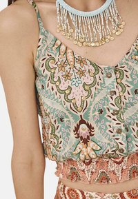 Top corto sin mangas de tela con patrón floral, que presenta colores pastel, botones en la parte delantera y un dobladillo fruncido con un acabado texturizado.