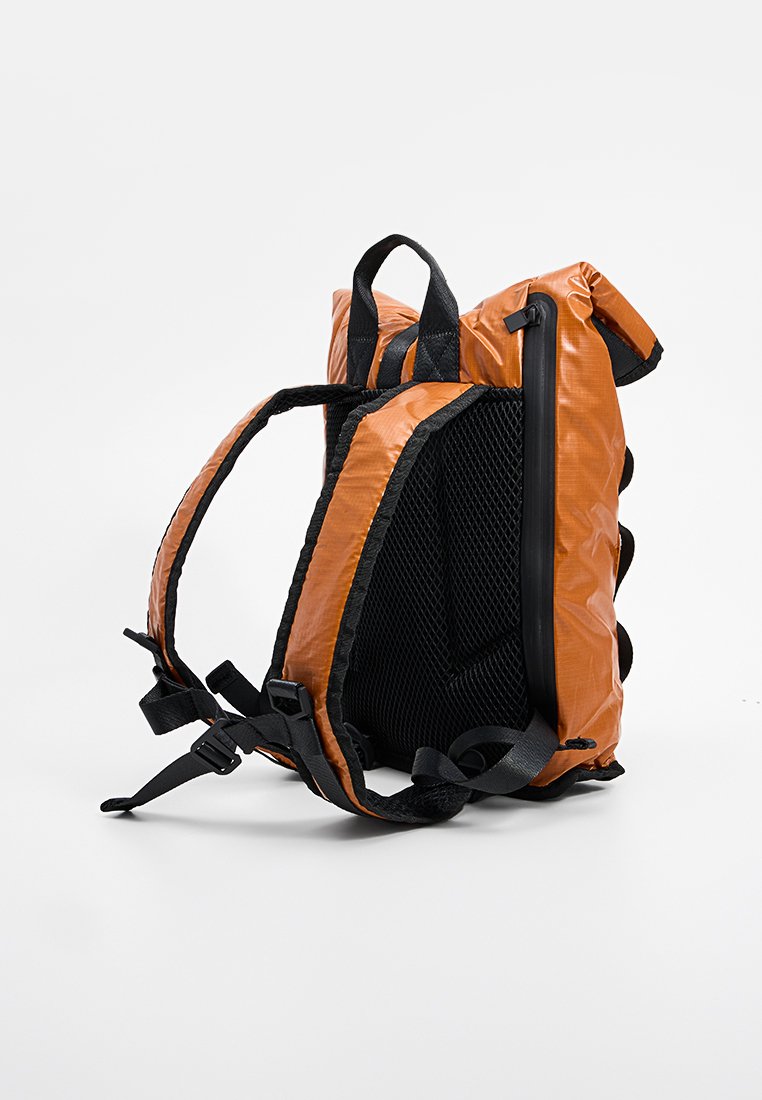 Zaino tecnico arancione e nero con spallacci imbottiti, pannello posteriore in rete, maniglia superiore e tasca laterale con zip, in piedi su uno sfondo bianco.