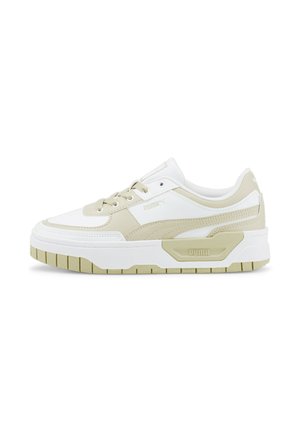 Witte en beige sneaker met een gestructureerde bovenkant, gevoerde kraag en dikke zool met een patroon voor grip. Puma-logo aan de zijkant.