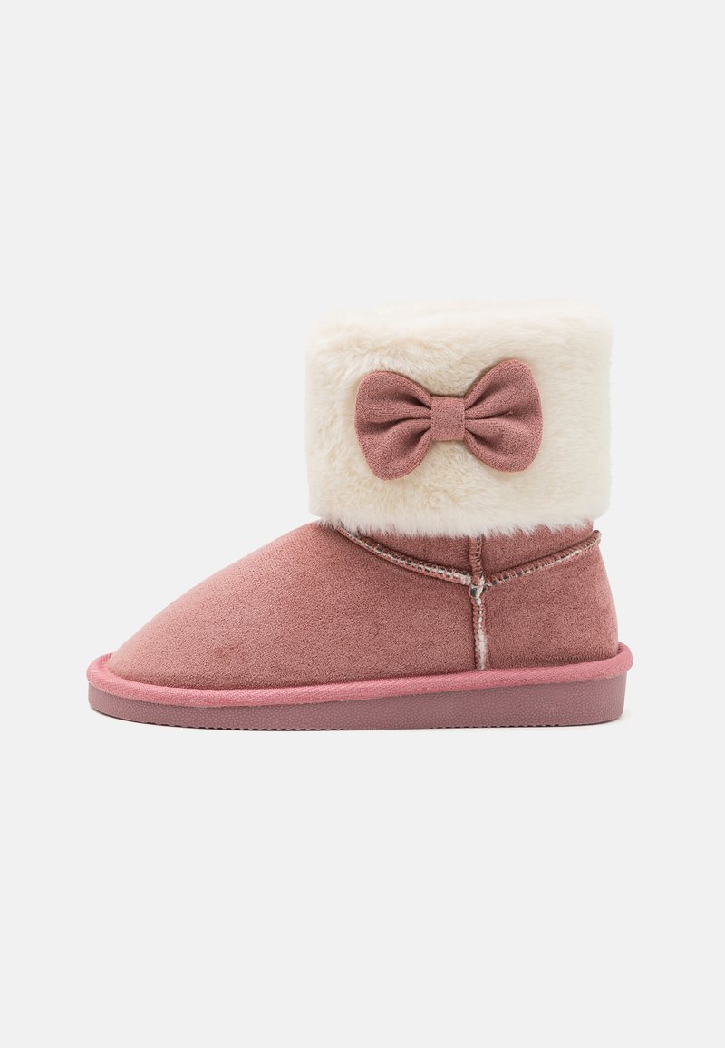 Botte en daim rose avec une manche en fourrure crémeuse, ornée d'un nœud à l'arrière et d'une semelle en caoutchouc durable. Design à bout arrondi.