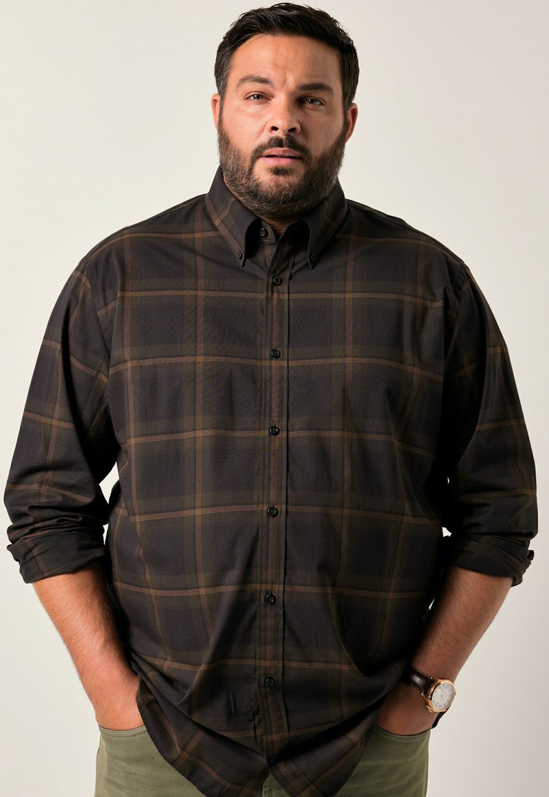 Donker geruite shirt in bruin en zwart, met een button-down kraag, lange mouwen en zwarte knopen. Casual gedragen over groene broek.
