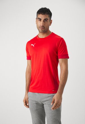 Red athletic t-shirt with short sleeves, made of smooth fabric. Features a white Puma logo on the chest. Paired with grey shorts.